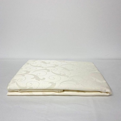 Toalha de mesa branca dobrada com padrão floral em relevo.