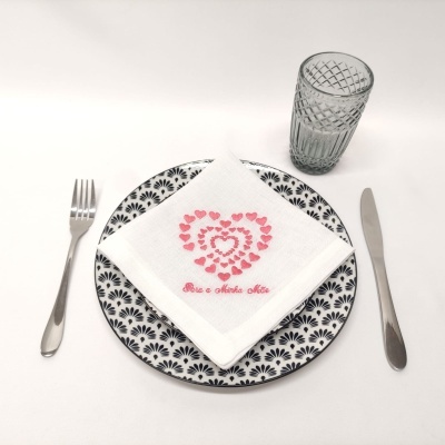 Mesa posta com prato decorado, guardanapo bordado, talheres e copo