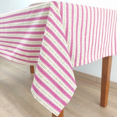 Toalha de mesa com riscas rosa, branco e dourado pendurada sobre mesa de madeira