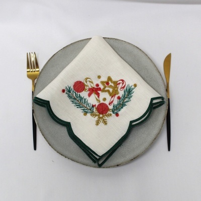 Guardanapo de tecido branco bordado natalício em prato cinzento com talheres dourados e pretos