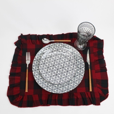 Conjunto de mesa com prato, talheres, copo e individual xadrez vermelho e preto.