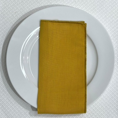 Prato branco com toalha de tecido amarelo mostarda dobrada