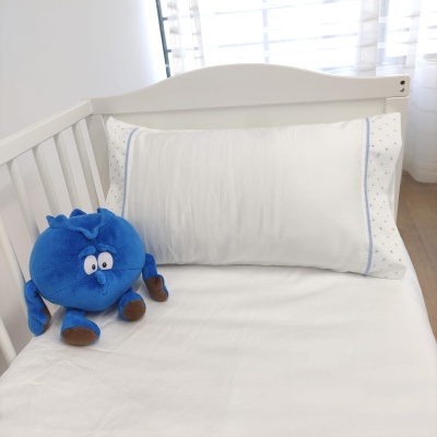 Berço branco com almofada branca bordada e peluche azul