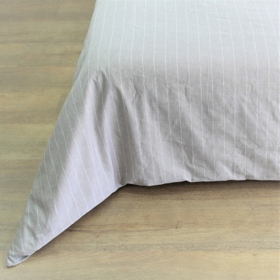 Canto de edredão cinzento claro com riscas brancas verticais em chão de madeira clara