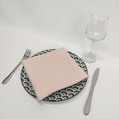 Conjunto de jantar com prato padrão azul e branco, guardanapo rosa, talheres metálicos e copo de vidro