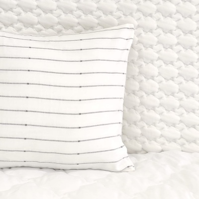 Almofada branca com riscas cinzentas horizontais num sofá branco acolchoado