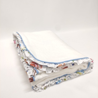 Manta branca dobrada com borda azul e padrão colorido nas bordas