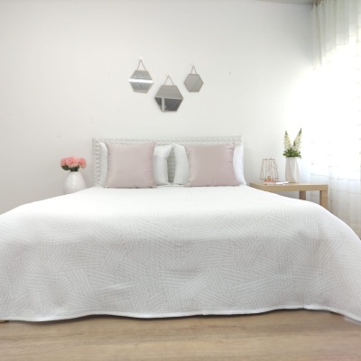Cama com colcha branca e almofadas cor-de-rosa e brancas numa decoração simples e moderna
