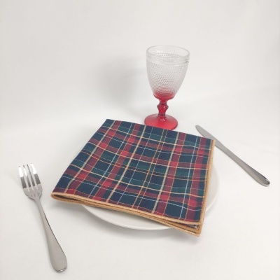 Conjunto de mesa com prato, talheres, guardanapo xadrez e copo de vidro texturizado em fundo branco