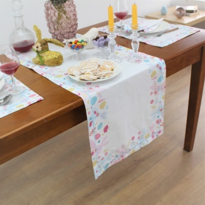 Corredor de mesa branco com padrão floral colorido sobre mesa de madeira com objetos decorativos e pratos.