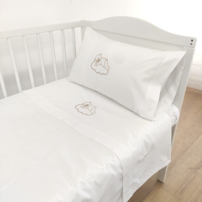 Cama de bebé branca com lençóis e fronha bordados com elefante