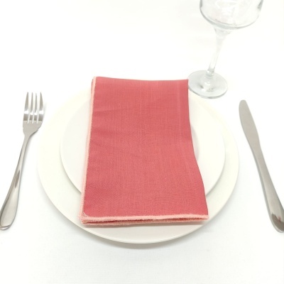 Conjunto de loiça com pratos, guardanapo vermelho, talheres de inox e copo transparente.