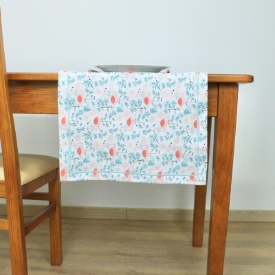 Toalha floral azul e rosa pendurada numa mesa de madeira