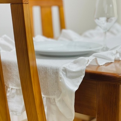 Mesa de madeira com roupa de mesa branca e pratos brancos