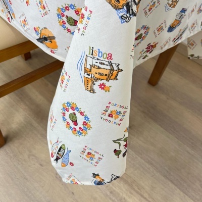 toalha de mesa branca com estampados coloridos de ícones portugueses e textos Lisboa e Portugal