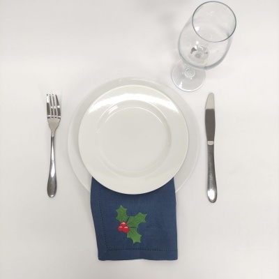 Conjunto de jantar com prato, talheres, copo e guardanapo bordado numa mesa branca