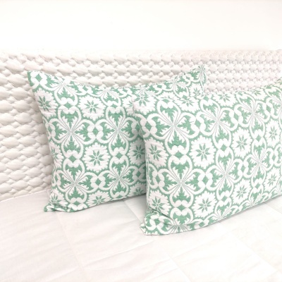 Duas almofadas retangulares florais verdes e brancas sobre colchão branco