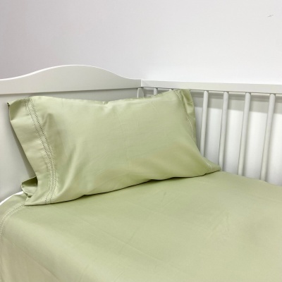 Jogo de cama verde claro em cama branca com cabeceira de ripas.