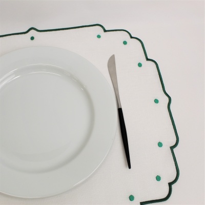 Conjunto de guardanapo branco com detalhes verdes, prato branco e faca com cabo preto