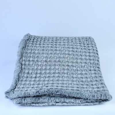 Cobertor cinzento com padrão quadriculado e franjas