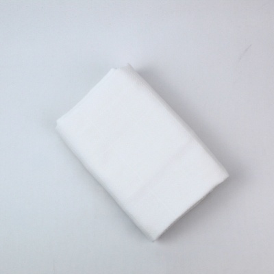 Toalha ou tecido branco dobrado sobre superfície branca