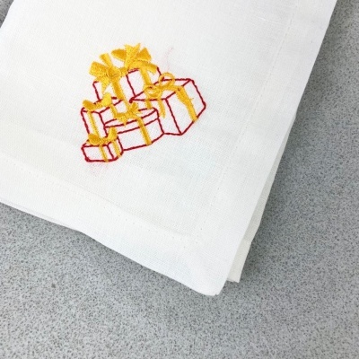 Guardanapo branco com bordado de presentes amarelos e vermelhos