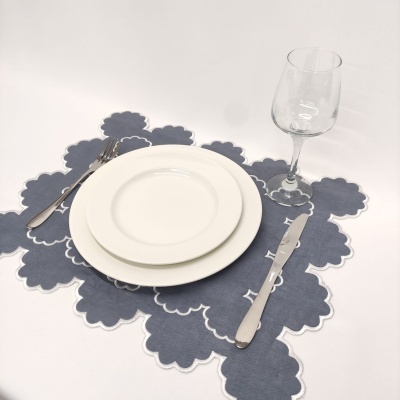 Jogo americano azul com pratos brancos, talheres e taça de vidro