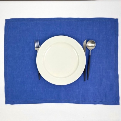 Jogo americano azul com prato branco e talheres