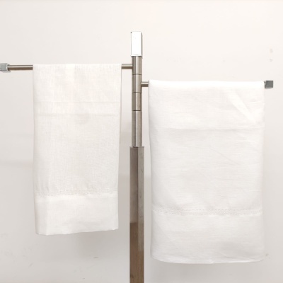 Duas toalhas de banho brancas penduradas em suportes metálicos prateados