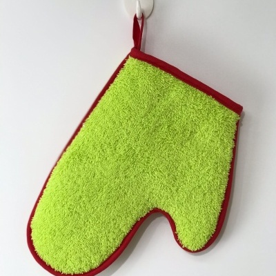 Luva de cozinha verde com bordas vermelhas pendurada numa parede