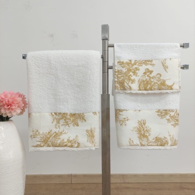 Toalhas de banho brancas com padrão floral dourado penduradas em suporte metálico
