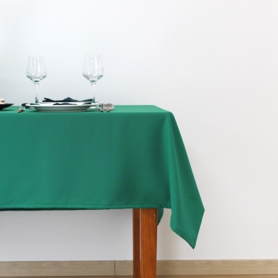 Toalha de mesa verde com conjunto de jantar minimalista sobre mesa de madeira