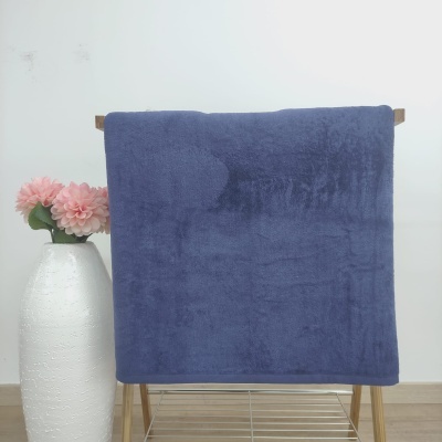 Manta azul felpuda pendurada em cabide com vaso branco e flores rosas ao lado