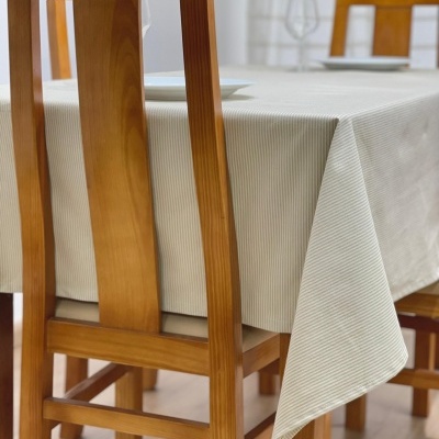 Mesa de madeira com toalha bege de riscas finas e cadeiras de madeira