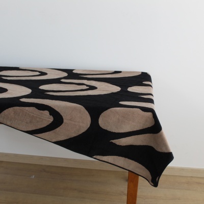 Toalha de mesa preta com círculos bege numa mesa de madeira