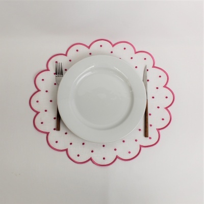 Prato branco com talheres sobre individual branco com bolinhas vermelhas e borda ondulada vermelha