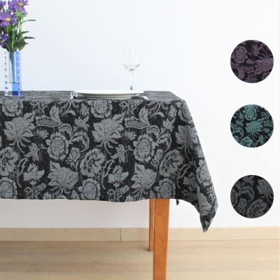 toalha de mesa retangular cinza com padrão floral em relevo em três opções de cor, posta numa mesa de madeira num ambiente minimalista