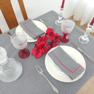 Mesa posta com toalha e guardanapos xadrez preto e branco e detalhes vermelhos