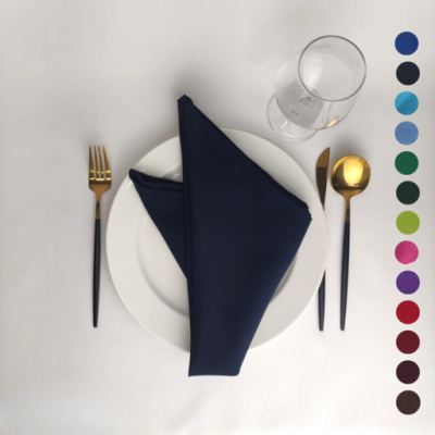 Conjunto de jantar com prato branco, guardanapo azul escuro, talheres preto e dourado, copo de vidro e paleta de cores