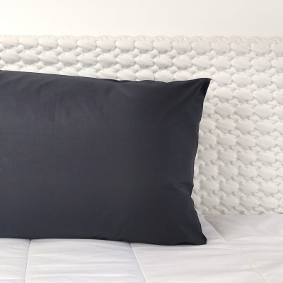 Travesseiro preto numa cama branca acolchoada com padrão hexagonal