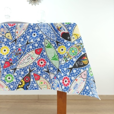 Toalha de mesa colorida com padrão de peixes e flores sobre mesa de madeira