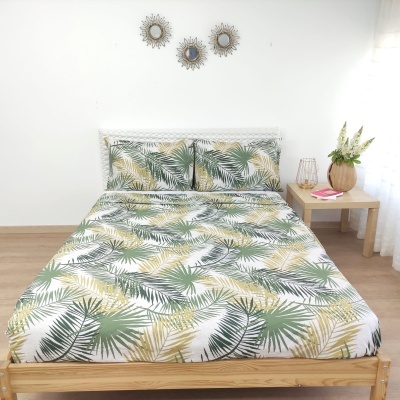Conjunto de roupa de cama com padrão de folhas verdes e amarelas em cama de madeira