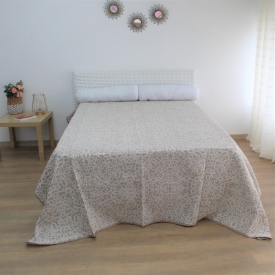 Cama com colcha bege floral e almofadas brancas em quarto minimalista