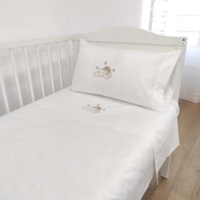 Cama infantil com roupa de cama branca e bordados de animais