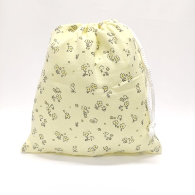 Saco de tecido amarelo claro com padrão floral e cordão branco