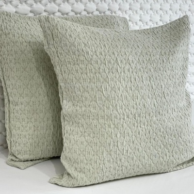 Duas almofadas cinza claro com padrão entrelaçado sobre superfície branca e fundo texturizado
