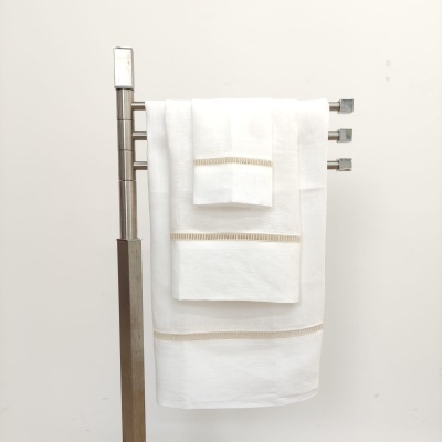 Três toalhas de banho brancas com bordados bege penduradas em suporte metálico