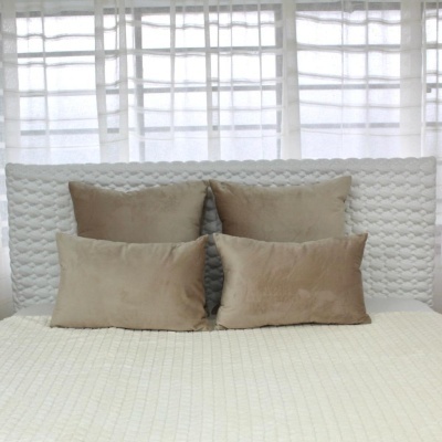 Travesseiros castanhos em cama branca com cortinas ao fundo