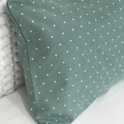 Travesseiro verde com pontos brancos em superfície branca acolchoada