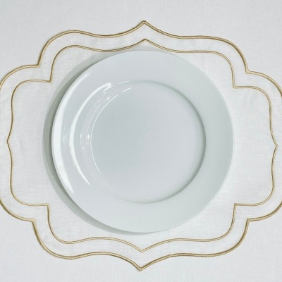 Prato branco redondo sobre tecido branco com bordado dourado